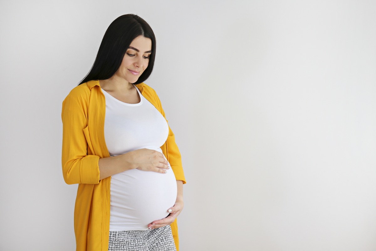 Pregnant woman, hands on belly, warm natural light